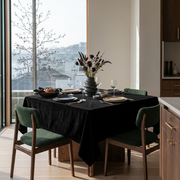 Black Square Velvet Tablecloth in a Contemporary Dining Room with Floor-to-Ceiling Windows and Green Upholstered Chairs