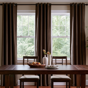 Warm dining room with chocolate brown grommet curtains, dark wooden furniture, and natural light.