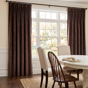 Elegant dining room with chocolate brown pinch-pleat curtains, classic furniture, and soft natural light.