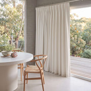 Cream Linen Pinch Pleat Dining Room Curtain in a Contemporary Dining Room with Grey Brick Walls and a Minimalist White Table Paired With a Woven Wood Chair - Blackout Lining