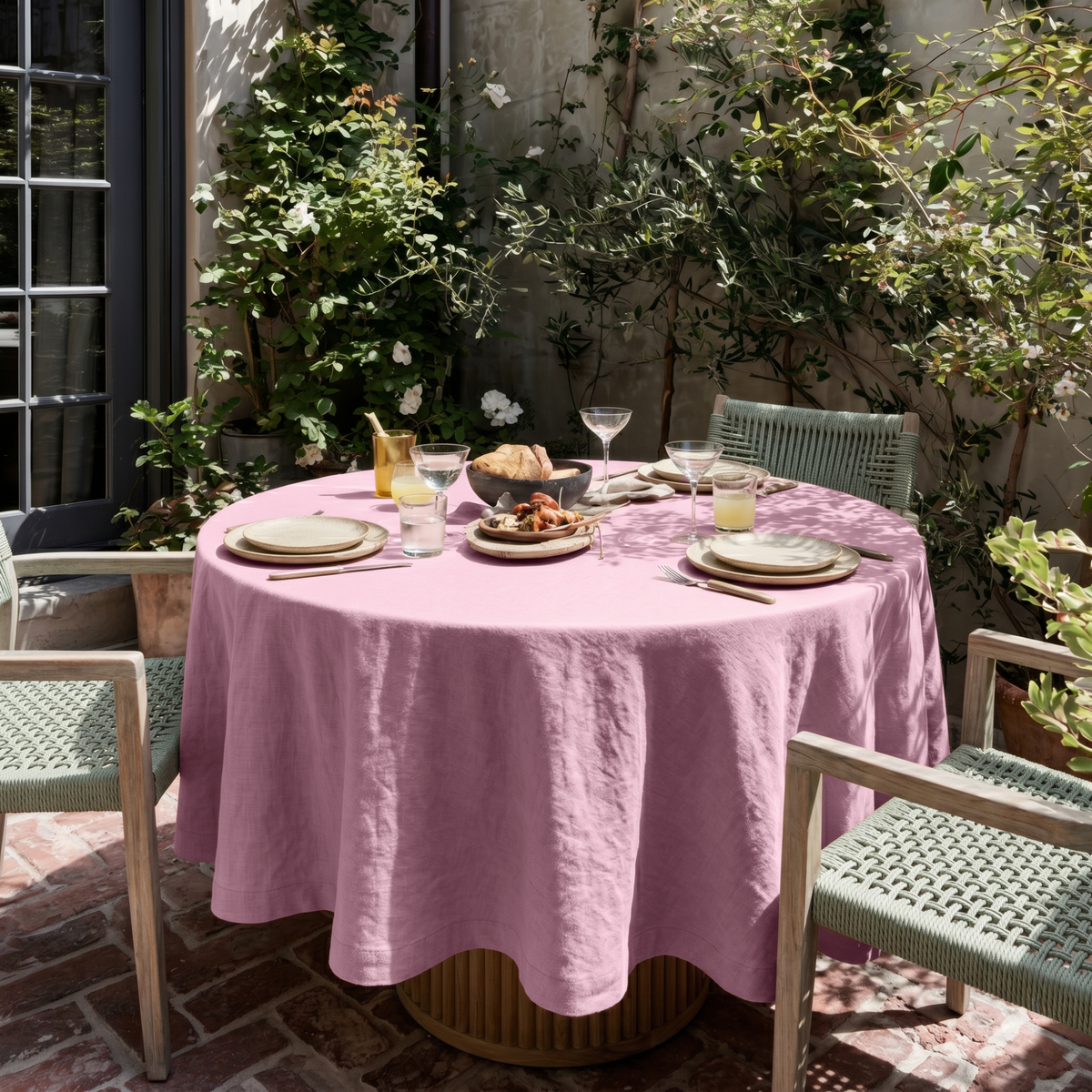 Dusty Rose Linen Round Tablecloth in a Sunlit Patio Dining Space with Sage Green Woven Chairs