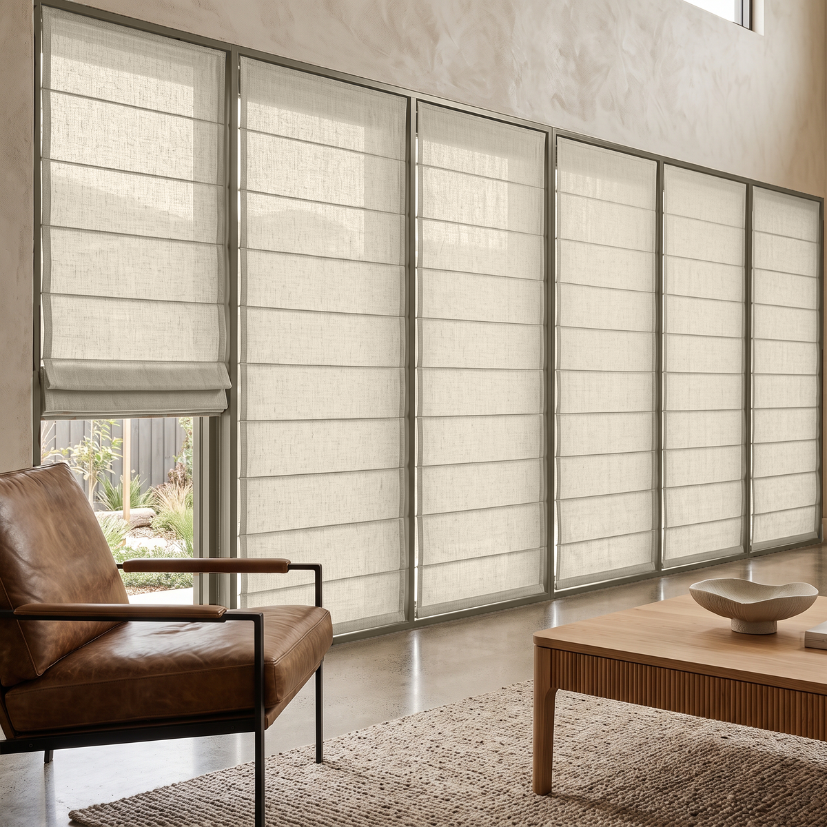 Heavy Ecru Roman Blinds in a Modern Living Room with Textured Gray Walls and a Leather Armchair
