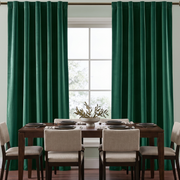 Elegant dining room with emerald green back-tab curtains, dark wooden furniture, and neutral chairs.
