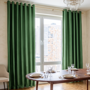 Elegant dining room with deep green grommet curtains, modern wooden furniture, and a city view.

