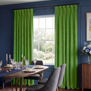 Bold dining room with bright green pinch-pleat curtains, navy walls, and elegant modern furniture.
