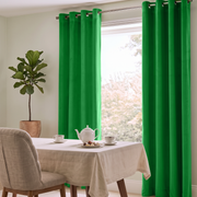 Cheerful dining room with vivid green grommet curtains, neutral furniture, and soft natural light.
