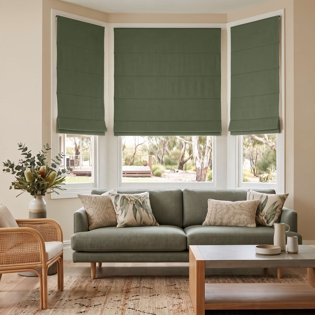 Sage Green Cordless Linen Roman Blinds in a Modern Living Room with Cream Walls and Rattan Armchair