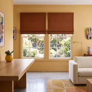 Terracotta Heavy Weight Linen Cordless Roman Blinds in a Modern Living Room with Warm Yellow Walls and Light Beige Armchair