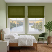 Moss Green Roman Blinds in a Light Green Bedroom with White Bedding and Green Armchair