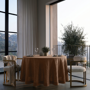 Tawny Brown Linen Round Tablecloth in an Airy Dining Room with Soft Greige Walls and Cream Bouclé Chairs