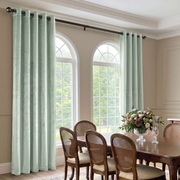 Elegant dining room with pale mint grommet curtains, cane-back chairs, and graceful arched windows.
