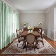 Classic dining room with pale sage back-tab curtains, ornate wooden furniture, and elegant floral décor.