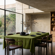 Moss Green Linen Rectangular Tablecloth in a Contemporary Dining Room with Floor-to-Ceiling Windows and Brown Leather Chairs