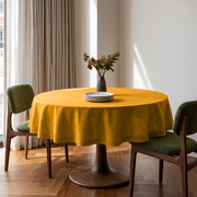 Mustard Yellow Linen Round Tablecloth in a Bright Dining Room with White Walls and Olive Green Bouclé Chairs
