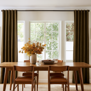Warm dining room with chocolate brown back-tab curtains, mid-century wooden furniture, and autumn décor