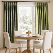Elegant dining room with olive green pinch-pleat curtains, cream chairs, and soft natural light.
