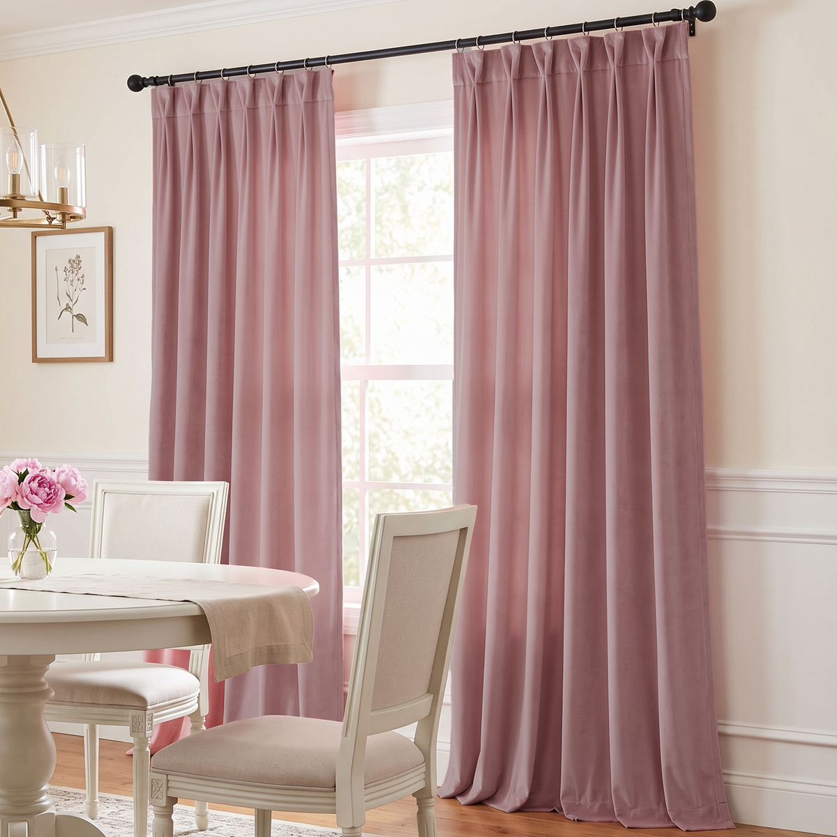 A soft, elegant dining room with dusty-pink curtains, a round white table, cream upholstered chairs, delicate floral décor, and warm natural light