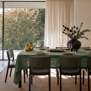 Sage Green Rectangular Linen Tablecloth in a Contemporary Dining Room with Floor-to-Ceiling Windows and Dark Leather Chairs