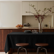 Black Rectangular Linen Tablecloth in a Modern Kitchen with Walnut Cabinetry and Wooden Stools