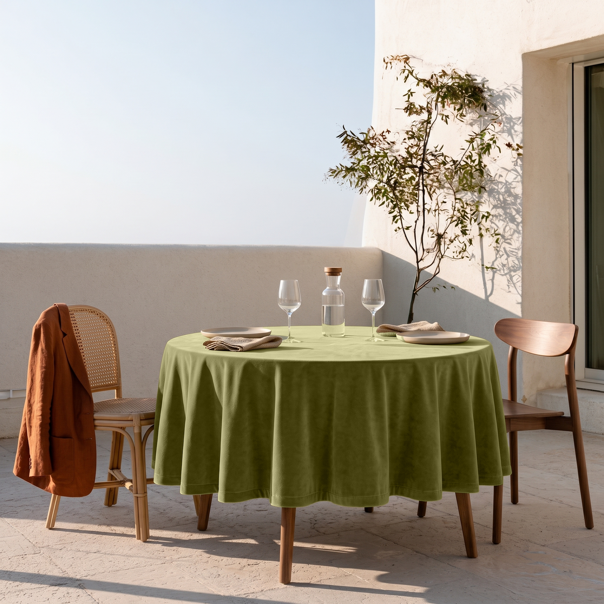 Moss Green Round Velvet Tablecloth on a Sunny Patio with White Stucco Walls and Wooden Chairs