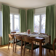 Bright dining room with sage green S-fold curtains, mid-century wooden furniture, and abundant natural light.
