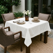 Off-White Square Linen Tablecloth on a Contemporary Patio with Wicker Chairs and Neutral Tableware
