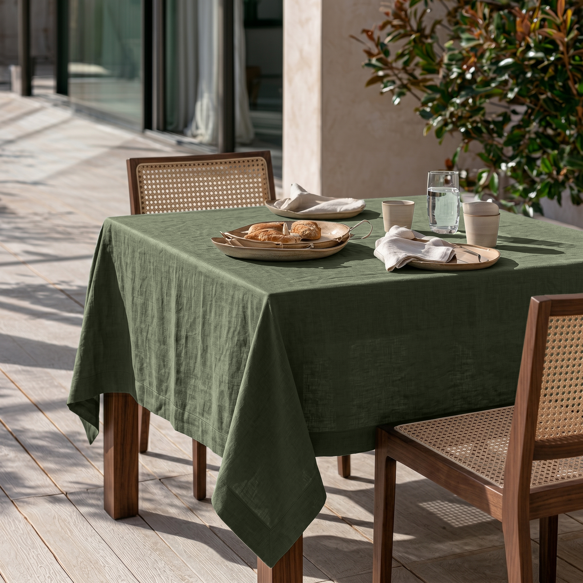 Sage Green Square Linen Tablecloth on a Modern Outdoor Terrace with Cane Chairs and Warm Wood Decking