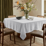 White Square Linen Tablecloth in a Warm Organic Dining Room with Cane Chairs and a Floral Centerpiece
