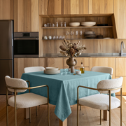 Aquamarine Blue Square Linen Tablecloth in a Contemporary Kitchen with Light Wood Cabinetry and Cream Upholstered Chairs