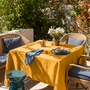 Mustard Yellow Square Linen Tablecloth in a Contemporary Outdoor Dining Area with Rattan Chairs