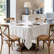 Off-White Square Linen Tablecloth in a Transitional Dining Room with Wooden Cross-Back Chairs