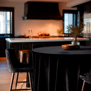Black Velvet Round Tablecloth in a Moody Kitchen Dining Area with White Tile Walls and Black Cabinetry