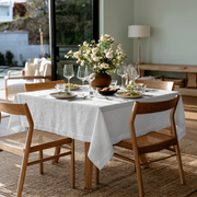 White Square Linen Tablecloth in a Bright Modern Dining Room with Wooden Chairs and a Garden View